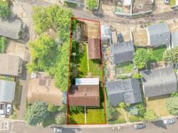 Aerial view showcasing a residential property with a main structure and an accessory building, featuring a substantial grassy yard - 
