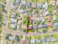 Aerial view showcasing the property outlined in red, featuring a rectangular lot with a primary residence and a detached structure - 