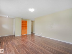 Spacious room featuring wood-finish flooring, a built-in orange shelving unit with integrated lower cabinetry, and flush-mount ceiling lighting - 