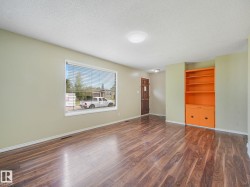 Spacious living area featuring wood-finish flooring, a large window with blinds, and recessed lighting - 