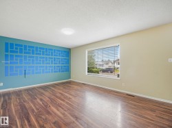 Spacious room featuring wood-finish flooring, a decorative accent wall, and neutral painted walls - 