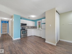 Kitchen area featuring wood-finish flooring, white cabinetry, and stainless steel appliances - 