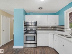 Kitchen featuring white cabinetry, light countertops, wood-finish flooring, stainless steel range, and an integrated microwave - 