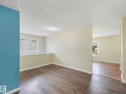 Spacious room featuring wood-finish flooring, light-toned walls, and a prominent accent wall - 