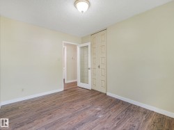 Spacious room featuring wood-finish flooring, light-toned walls, and a textured ceiling - 