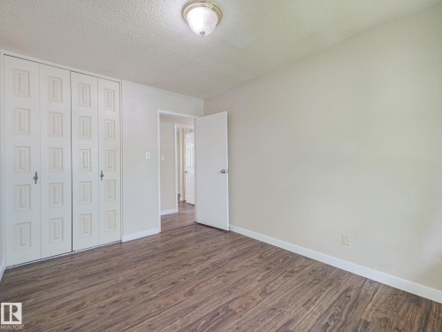 Room featuring wood-finish flooring, light-toned walls, and white baseboards - 9315 151 Avenue, Edmonton, AB 