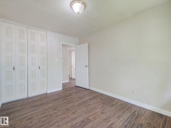 Room featuring wood-finish flooring, light-toned walls, and white baseboards - 