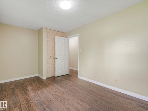 Spacious room featuring wood-finish flooring, light-toned walls, and a ceiling-mounted light fixture - 9315 151 Avenue, Edmonton, AB 