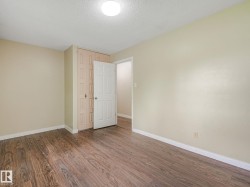 Spacious room featuring wood-finish flooring, light-toned walls, and a ceiling-mounted light fixture - 