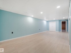 Spacious room featuring light blue panel walls, recessed lighting, wood-finish flooring, white baseboards, and a double-door closet - 