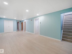 Spacious room featuring light wood-finish flooring, recessed lighting, and light blue vertical plank wall paneling - 