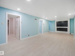 Spacious interior featuring light wood-finish flooring, recessed lighting, and a modern fireplace with a marble-look surround - 