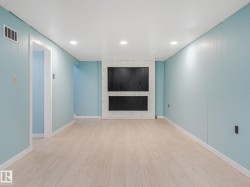 Spacious room featuring wood-finish flooring, light blue vertical paneling, and a white ceiling with recessed lighting - 