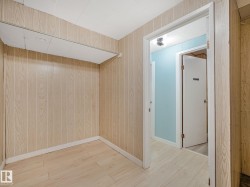 Room featuring wood-look paneling, light wood-finish flooring, and a white ceiling - 