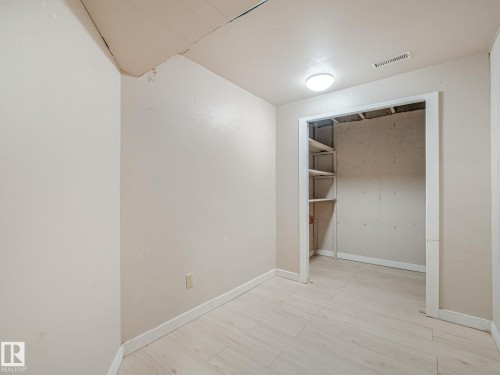 Room featuring light-toned walls, wood-finish flooring, and a flush-mount ceiling light - 9315 151 Avenue, Edmonton, AB 