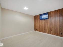 Interior room featuring a wood-finish accent wall, light-toned walls, light wood-finish flooring, and a drop ceiling with recessed lighting - 