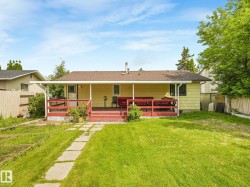 Rear exterior featuring an expansive covered deck, a spacious grassy lawn, and a stepping stone pathway - 