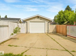 Detached single-car garage with a panel door, stucco exterior, and concrete driveway - 