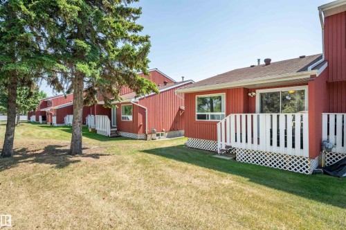 Red-sided exterior with a private deck, sliding glass door, and a ground-level window - 10678 Beaumaris Road Nw, Edmonton, AB 