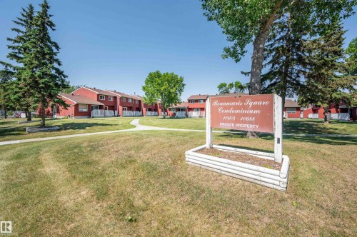 Expansive green space with mature trees and paved walkways, surrounded by multi-unit residences featuring private patios - 10678 Beaumaris Road Nw, Edmonton, AB 
