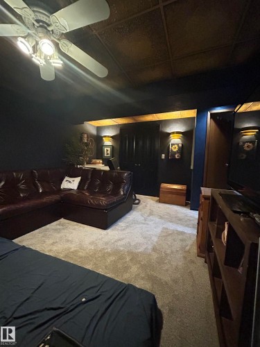 Recessed ceiling with decorative panels, wall-mounted sconce lighting, ceiling fan with integrated lighting, and neutral tone carpeting - 10678 Beaumaris Road Nw, Edmonton, AB 