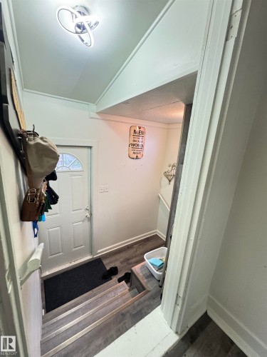 Entryway featuring a paneled door, wood-finish flooring, and a modern ceiling light fixture - 4912 49 Avenue, Onoway, AB 