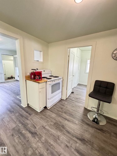 Kitchen area featuring wood-finish flooring, white cabinetry, and a white electric range - 4912 49 Avenue, Onoway, AB 