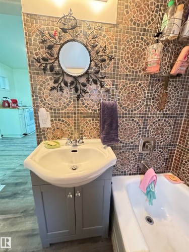 Bathroom featuring mosaic tile wall, white drop-in sink with gray vanity, and a white bathtub - 4912 49 Avenue, Onoway, AB 