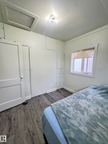 Room featuring wood-finish flooring, built-in cabinetry, a window with natural light, and a ceiling-mounted light fixture - 4912 49 Avenue, Onoway, AB 