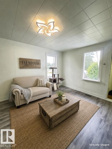 Bright living area featuring wood-finish flooring, white baseboards, and two windows - 4912 49 Avenue, Onoway, AB 