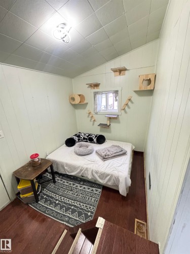 Compact room featuring dark wood-finish flooring, white paneled walls, and a white ceiling with a modern flush-mount light fixture - 4912 49 Avenue, Onoway, AB 