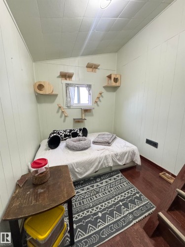 Compact room featuring wood-finish flooring, white paneled walls, and a white grid ceiling - 4912 49 Avenue, Onoway, AB 