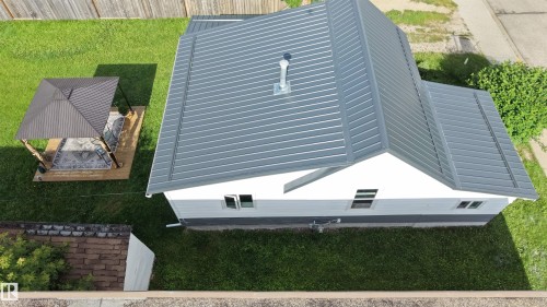 Property featuring a grey metal roof, white siding, and a contrasting dark grey foundation - 4912 49 Avenue, Onoway, AB 