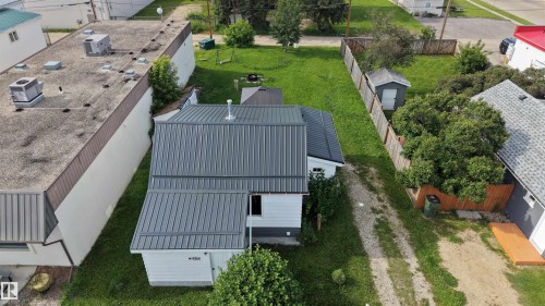 Property featuring a gray metal roof, white aluminum siding, and a spacious grassy yard - 4912 49 Avenue, Onoway, AB 