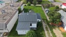 Property featuring a gray metal roof, white aluminum siding, and a spacious grassy yard - 4912 49 Avenue, Onoway, AB 