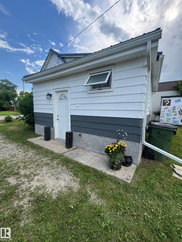 White aluminum siding exterior with a dark gray accent band and a light gray foundation - 4912 49 Avenue, Onoway, AB 