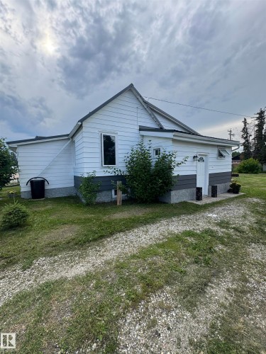 White siding exterior with a dark-pitched metal roof and a gravel driveway - 4912 49 Avenue, Onoway, AB 