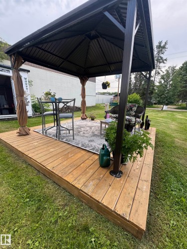 Expansive wooden deck featuring a gazebo with a dark metal frame and retractable fabric curtains - 4912 49 Avenue, Onoway, AB 