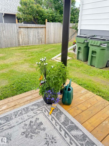 Ground-level wood-finish decking overlooking a grass yard with a perimeter wood fence - 4912 49 Avenue, Onoway, AB 