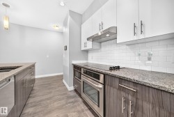 Contemporary kitchen featuring wood-finish lower cabinetry, white upper cabinetry, and stainless steel appliances - 