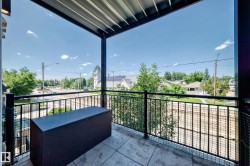 Covered balcony featuring stamped concrete flooring, black metal railings, and a slatted ceiling - 