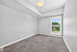 Carpeted room featuring a single window with white trim, light gray painted walls, and a tray ceiling with a flush-mount light fixture - 