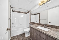 Bathroom featuring a wood-finish vanity with an undermount sink, granite countertop, and a full-width mirror - 