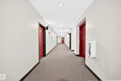 Hallway with light gray walls, dark red doors, and recessed ceiling lighting - 