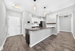 Open-concept kitchen featuring an eat-at peninsula with a granite countertop, white upper and dark lower cabinetry, and stainless steel appliances - 