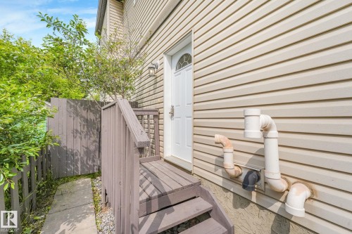 Side entrance featuring a privacy fence, exterior lighting, wood-finish steps, and a concrete pathway - 10216 150 Street Nw, Edmonton, AB - Outdoor