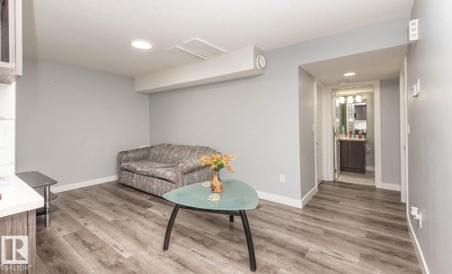 Versatile living area featuring wood-finish flooring, light gray walls, white trim, and recessed lighting - 2635 Donaghey Crescent, Edmonton, AB 