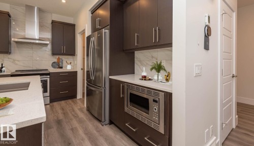 Contemporary kitchen featuring dark wood cabinetry, stainless steel appliances, and wood-finish flooring - 2635 Donaghey Crescent, Edmonton, AB 