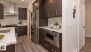 Contemporary kitchen featuring dark wood cabinetry, stainless steel appliances, and wood-finish flooring - 2635 Donaghey Crescent, Edmonton, AB 