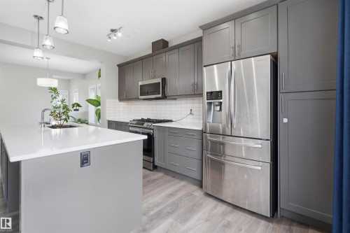 Kitchen island with white countertop, undermount sink, and pendant lighting - 1234 Daniels Crescent, Edmonton, AB - Indoor Photo Showing Kitchen With Stainless Steel Kitchen With Upgraded Kitchen